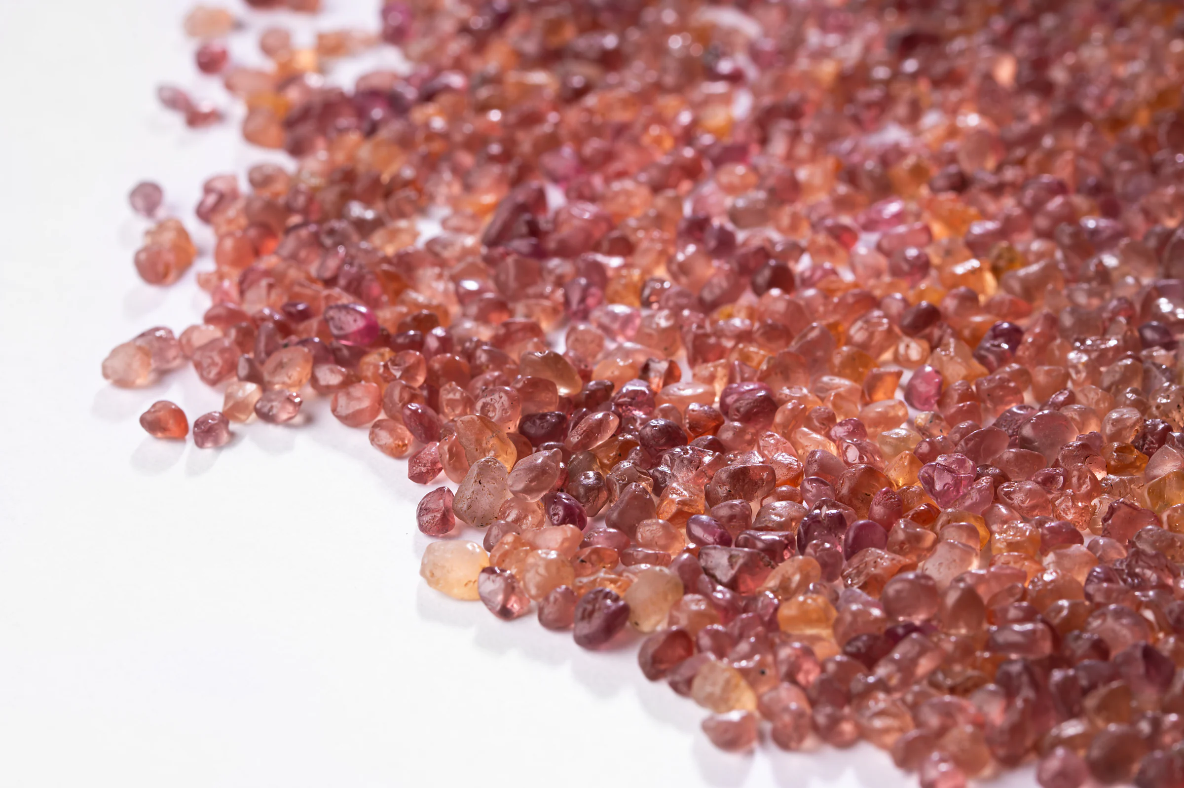 A drift of small rough Malaya garnets on white.