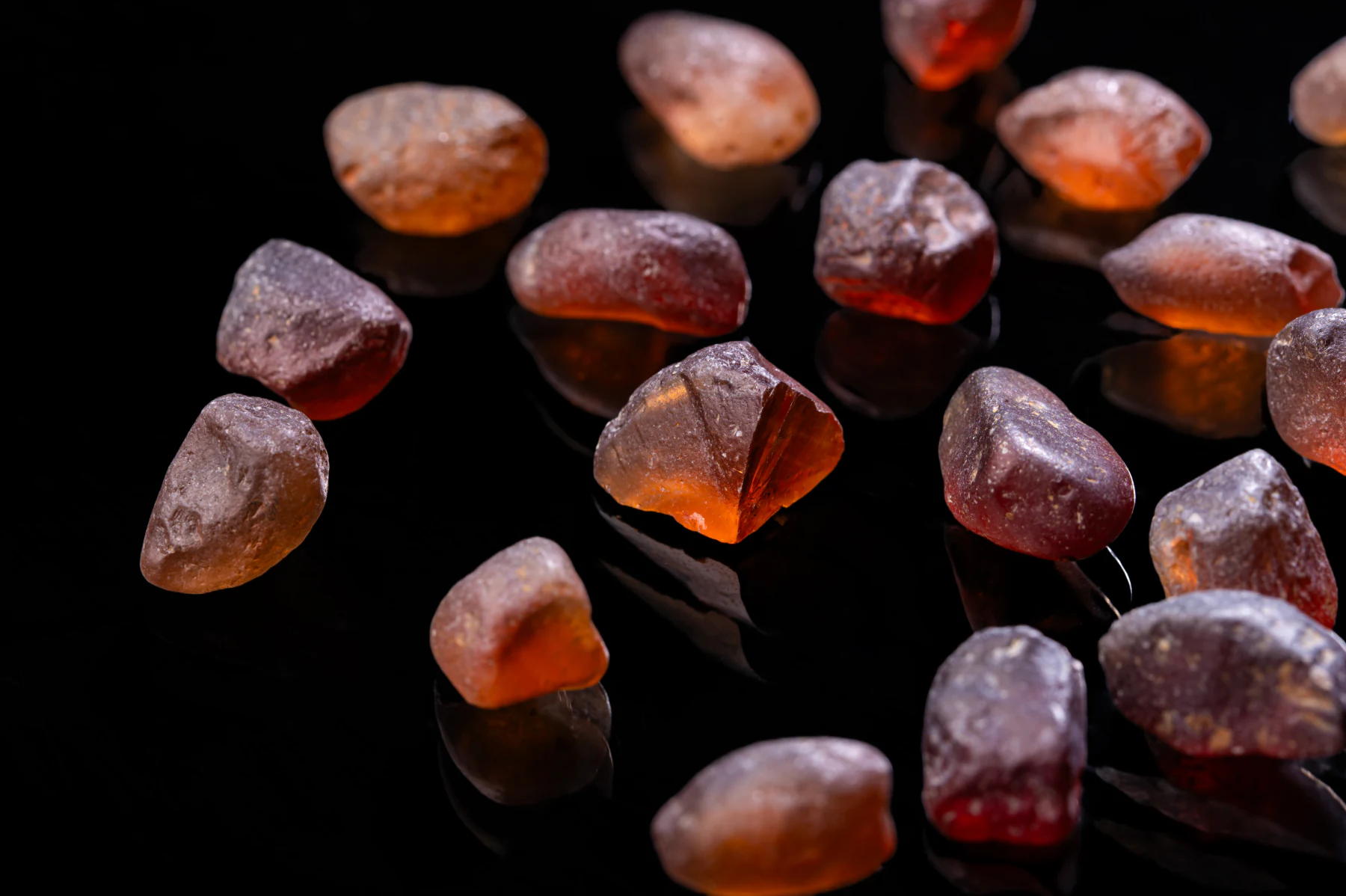 Rough Malaya garnet pebbles on black.