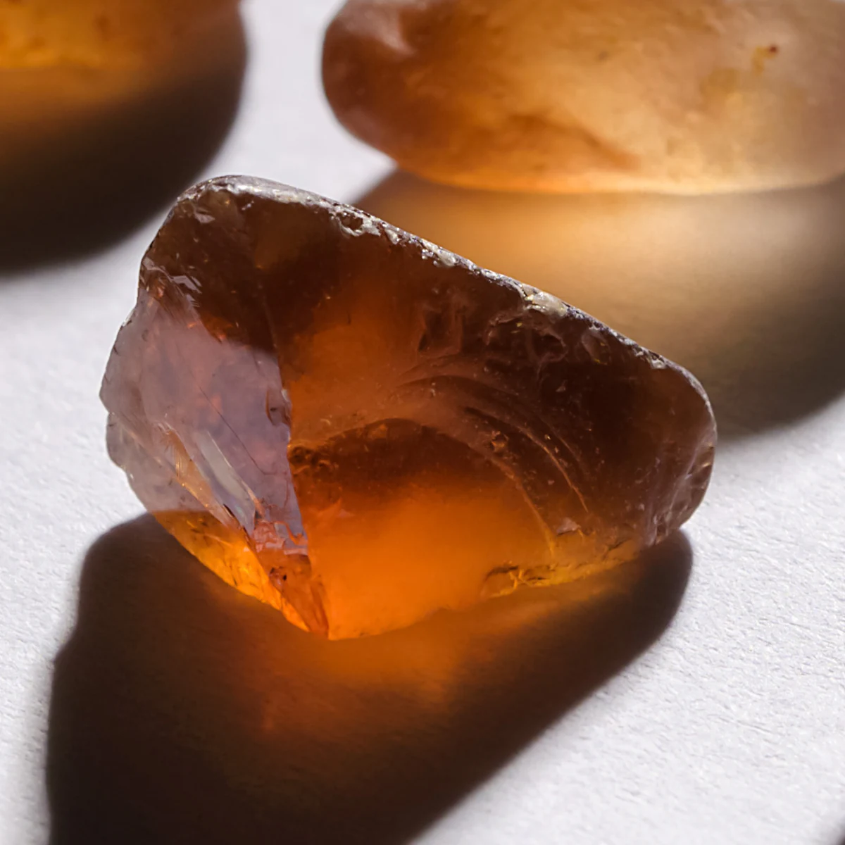 A single rough Malaya garnet on white, glowing amber.