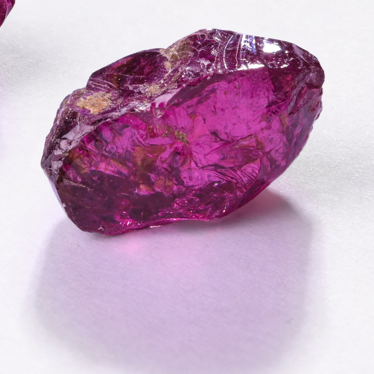 A single rough rhodolite on white.