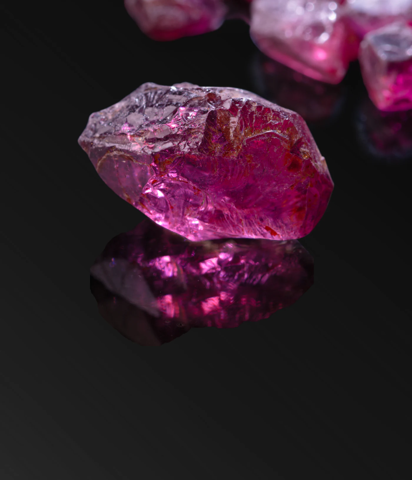 Rough rhodolite garnet on black.