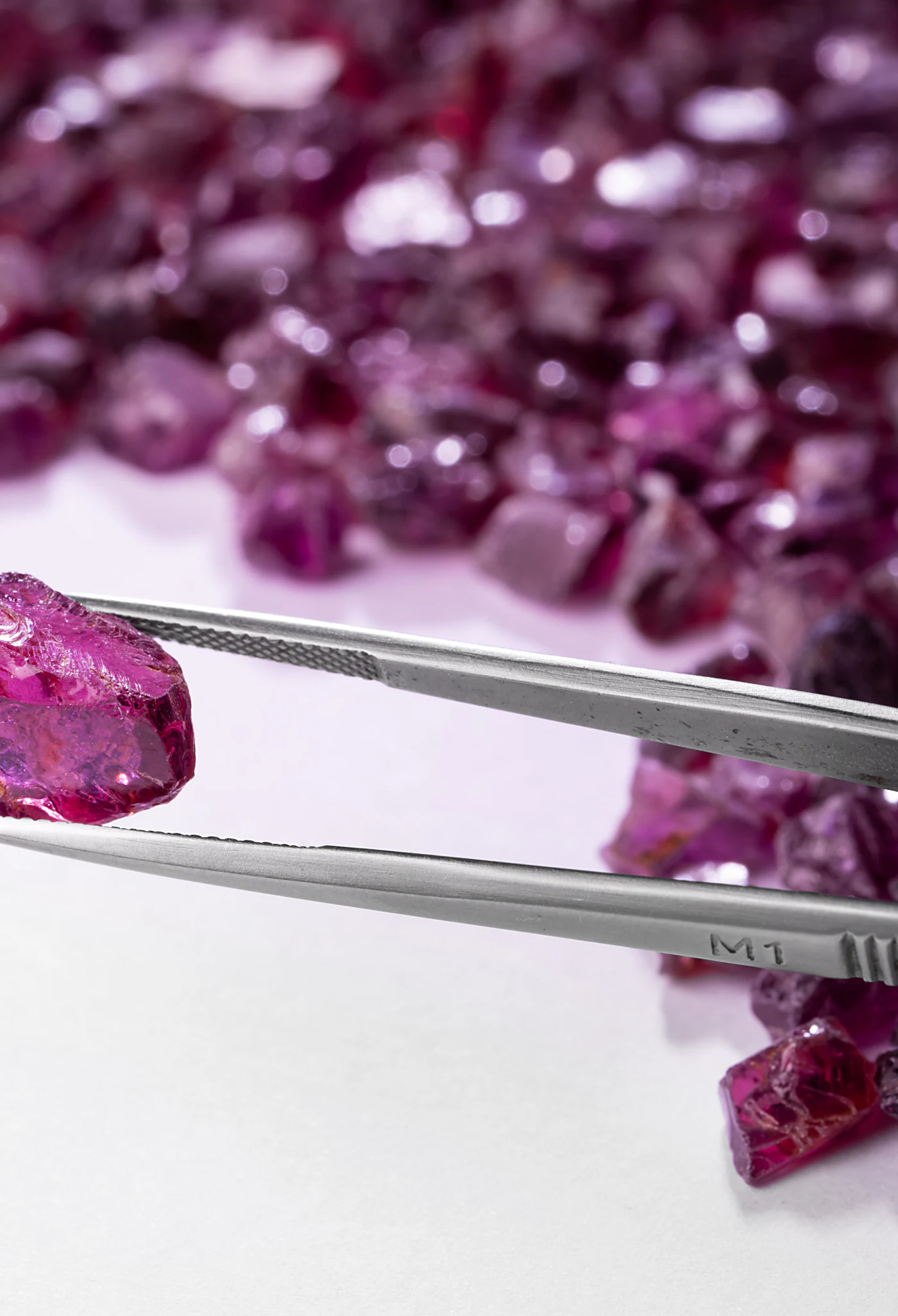 A pile of rough rhodolite garnets on white.