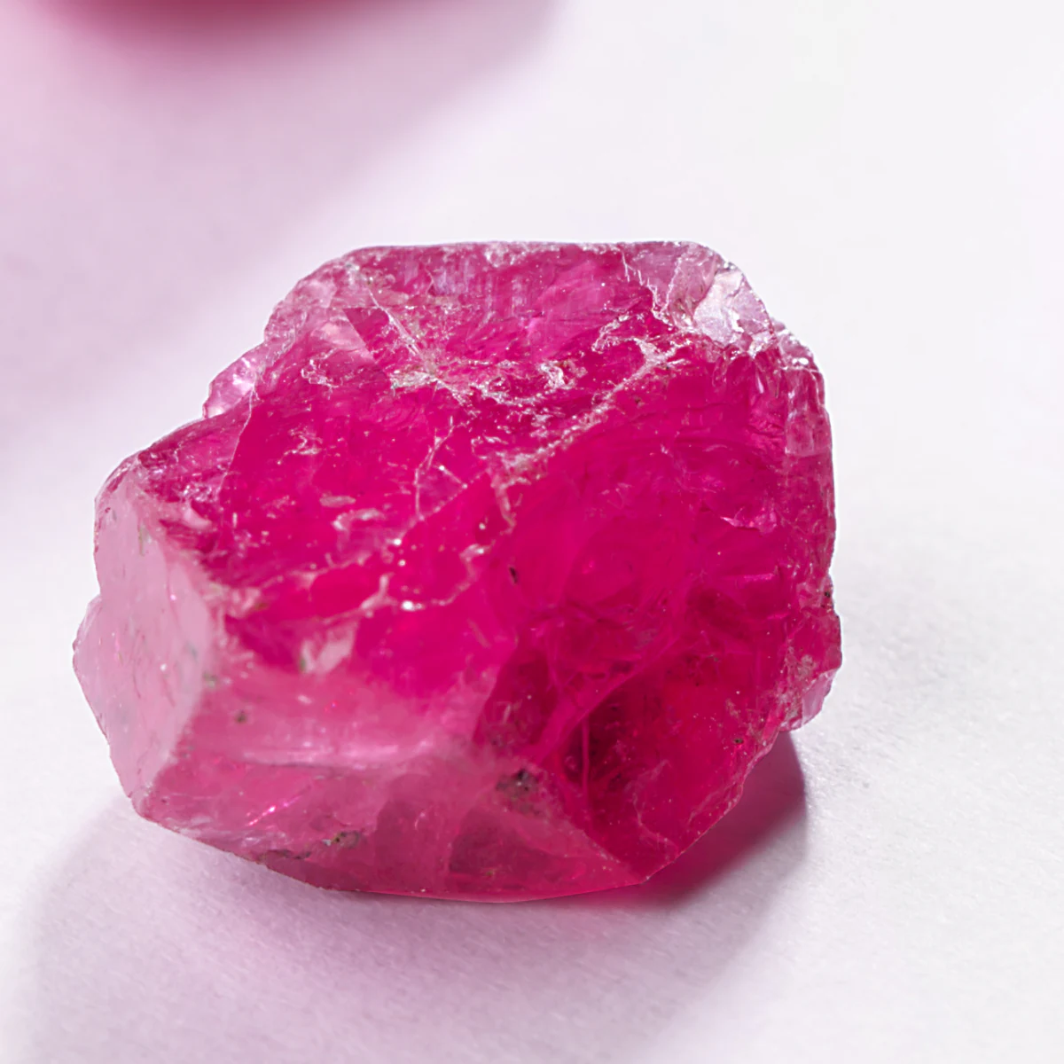 A single rough pink spinel on white.
