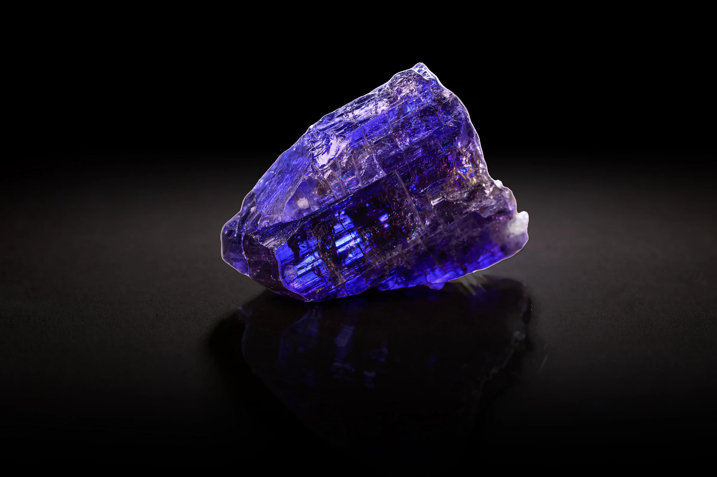 A rough tanzanite on black, glowing blue and violet.