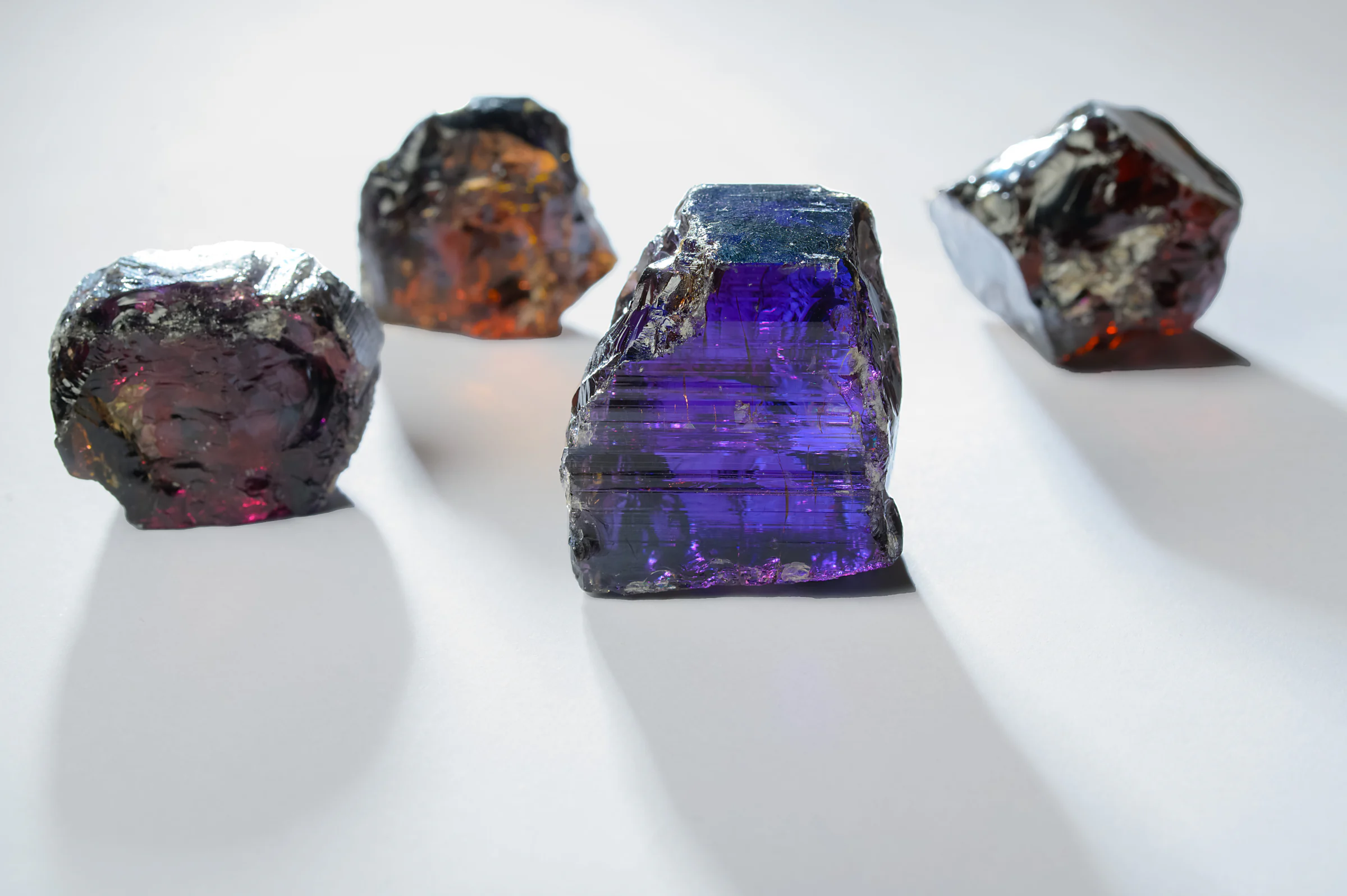Rough stones on a white table, one glowing violet among the darker crystals.