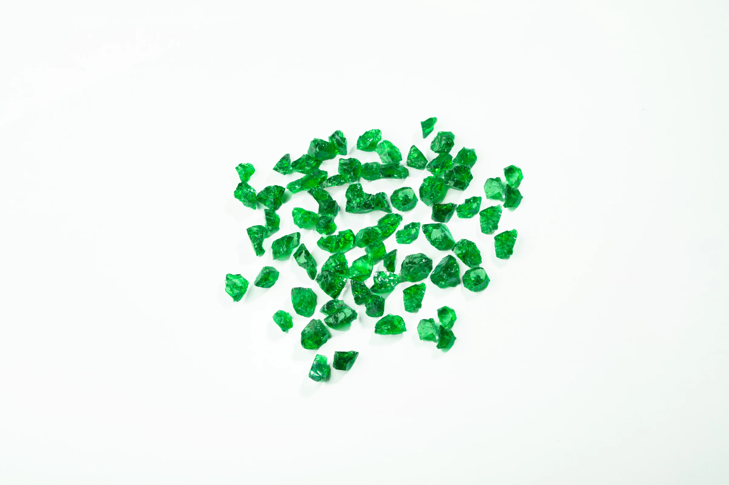 Rough tsavorite crystals scattered on white.