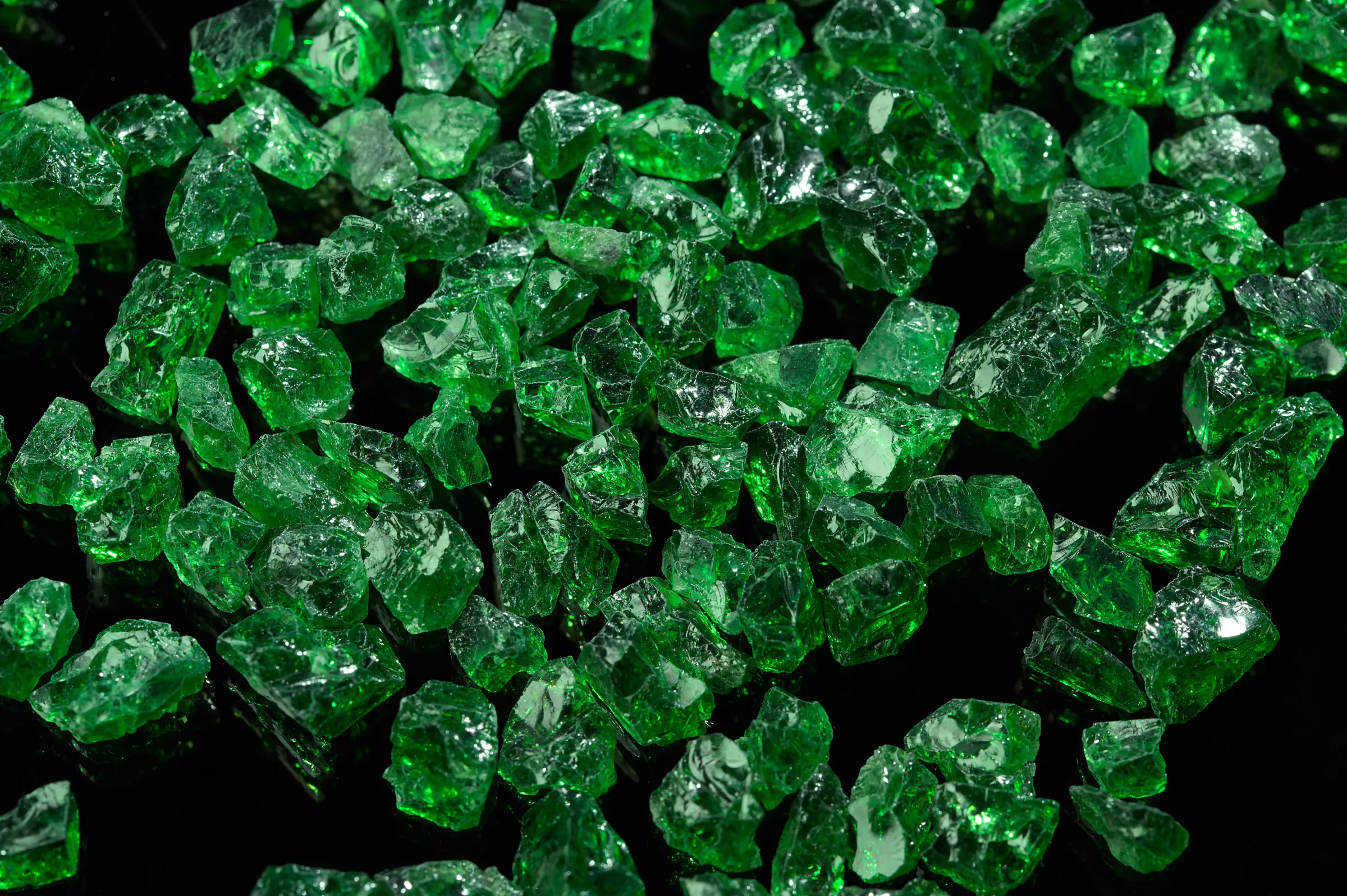 Rough tsavorite crystals glowing green on black.