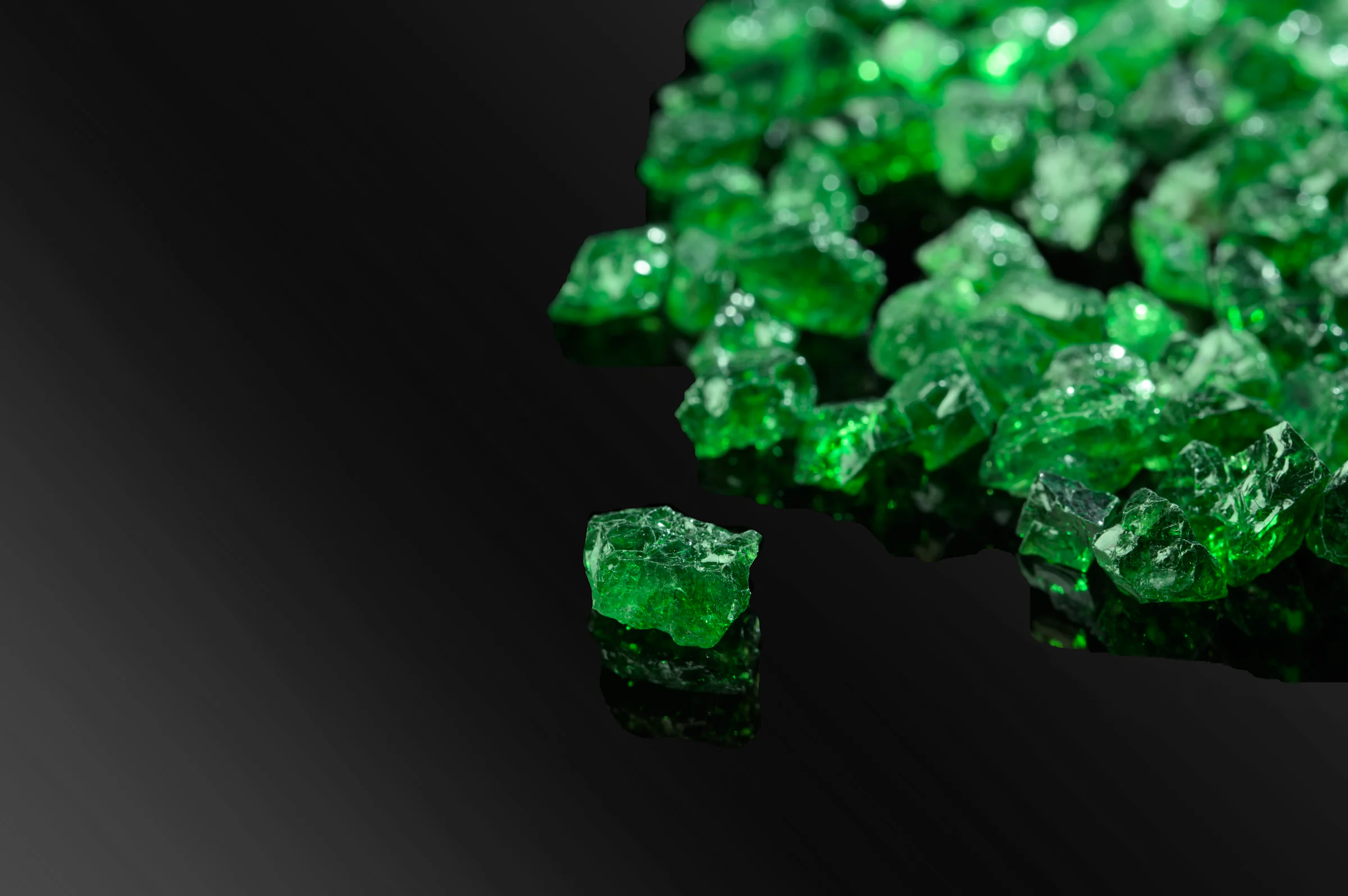 Rough tsavorite on black, one crystal set apart from the rest.