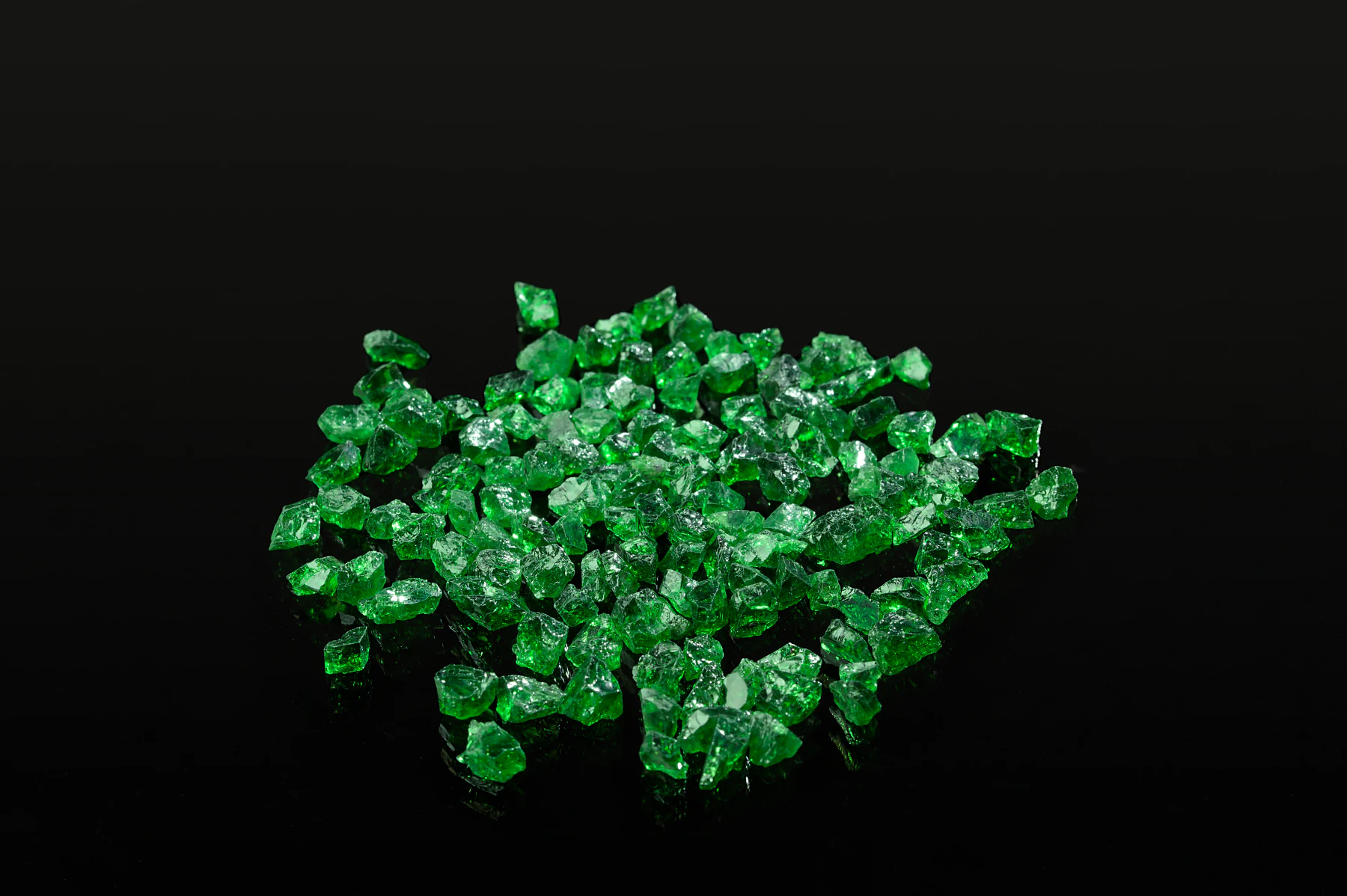 A heap of rough tsavorite on black.