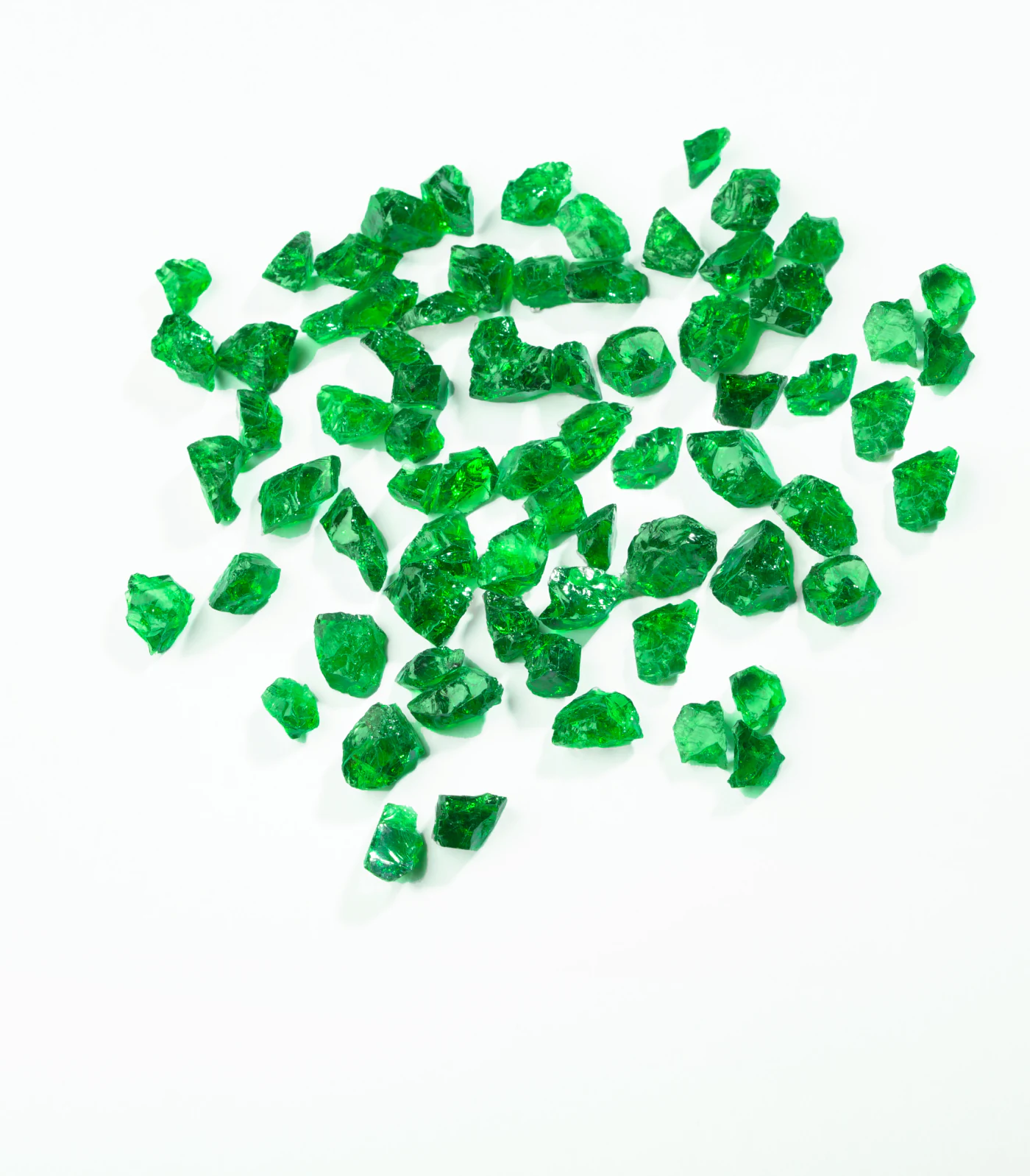 Rough tsavorite crystals scattered on white.